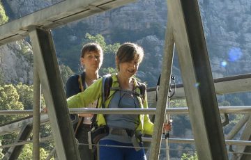 Randonneuse en aidant une autre à traverser un pont dans la montagne