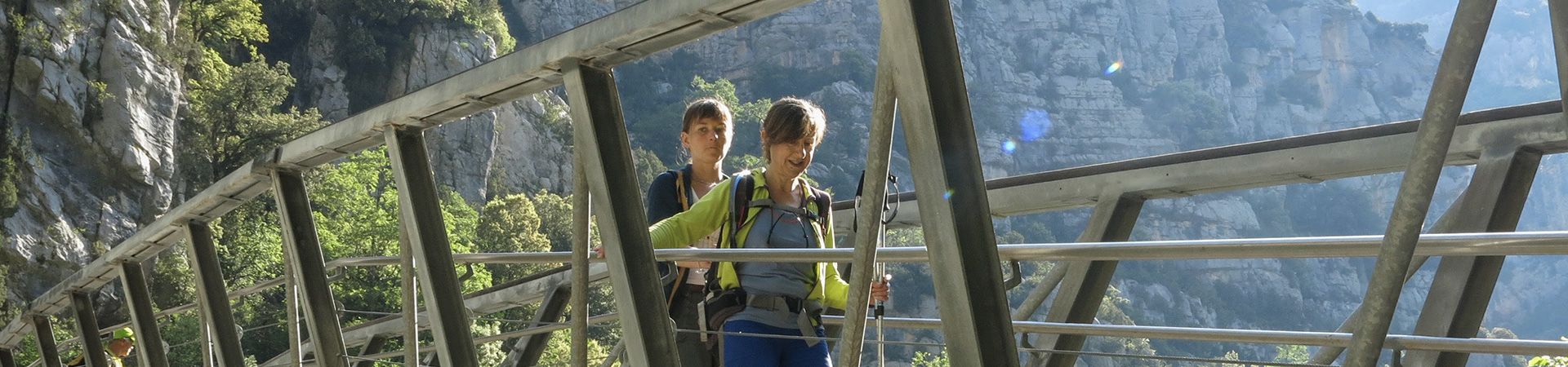 Randonneuse en aidant une autre à traverser un pont dans la montagne